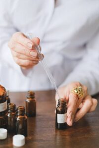 Close-up of hands using a dropper with brown glass bottles for essential oils.